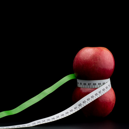 Home grown apples with meter ribbon on dark background