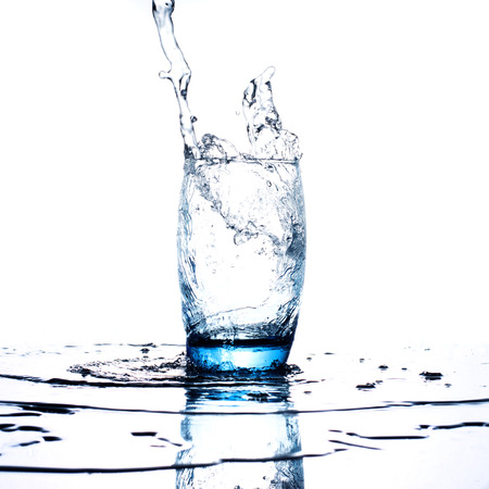 Water flowing and splashing into a glass