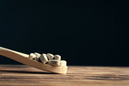 Vitamins or supplements in wooden spoon on vintage wooden boardの写真素材