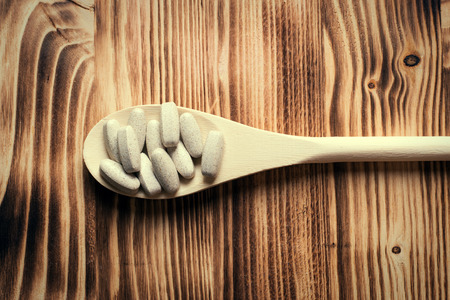 Vitamins or supplements in wooden spoon on vintage wooden boardの写真素材