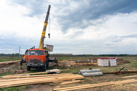 Unloading of from a big truck with a flat bed trailer. Steel rods, lumber, blocks, pipes - building materials for cottage constructionの写真素材