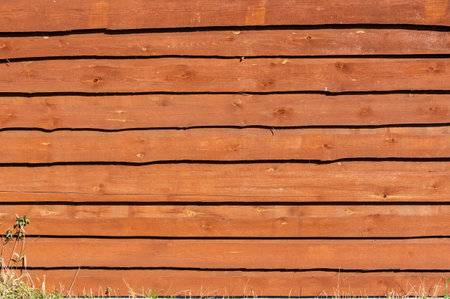 Wooden fence made of horizontal boards covered with stain, fire-retardant impregnation. Wooden backgroundの写真素材