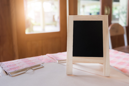 Rustic slate menu blackboard on wooden desk and morning light with blank screen and can be add your texts or others on slate.の写真素材
