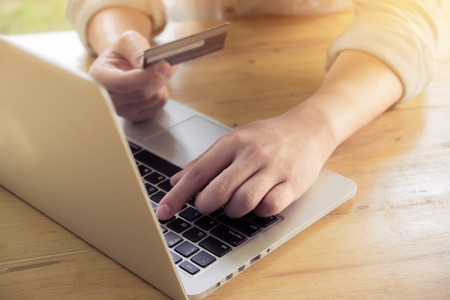 Man's hands holding a credit card and using pc or laptop for online shopping.の写真素材