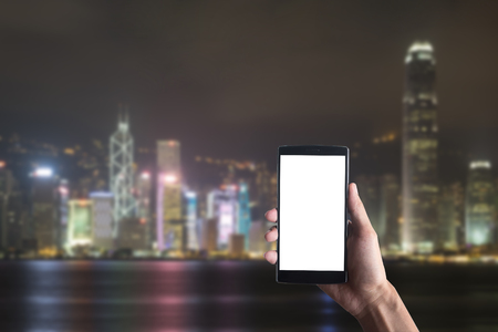 Happy man holding and showing blank smartphone with night bulding blur background. Smart phone with blank screen and can be add your texts or others on smart phone.の写真素材