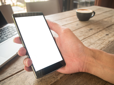 Hand holding smartphone with laptopの写真素材