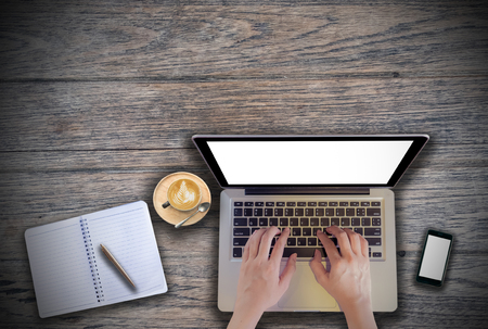 office desk mockup: laptop, smart phone, and cup of coffee and notebook with business financial graph on wooden background. View above shot. Vintage filter effect.の写真素材