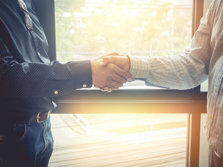 Business woman and partner shaking hands in office. vintage filter effect.の写真素材