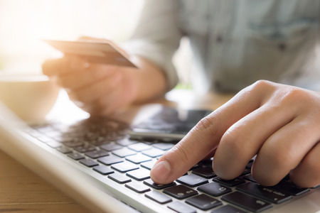 Man's hands holding a credit card and using pc or laptop for online shopping with morning light.の写真素材