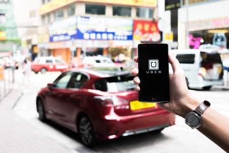 HONGKONG,CHINA - MAY 16,2016 : A man hand holding Uber app showing on LG G4 on road and red car,Uber...