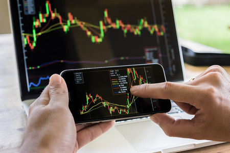 A businessman using a mobile device to check market graph.のeditorial素材