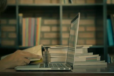 Business women reading book with laptop on wooden desk. vintage.の写真素材