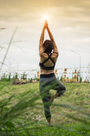 Young woman is practicing yoga at mountain in sunset. Healthy and relax concept.の写真素材