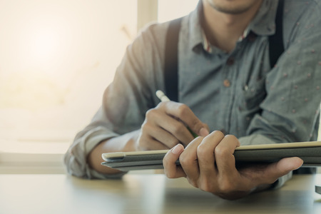 Interior designer hand working with new modern computer laptop and pro digital tablet with sample material board on wooden desk as conceptの写真素材