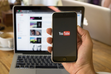 CHIANG MAI,THAILAND - JAN 26, 2017: A woman showing screen shot of Youtube on iphone 6s. YouTube app on the screen lying on old wood desk. YouTube is the popular online video sharing website.のeditorial素材