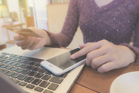 Online payment, Woman's hands holding a credit card and using smart phone for online shopping in...