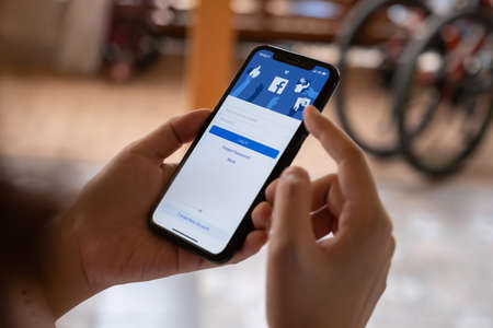 CHIANG MAI, THAILAND - FEB 26, 2020: Woman hold Apple iPhone XS with facebook application. Facebook is a social network and creating cryptocurrency name is Libra in 2019.のeditorial素材