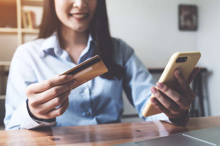 Online payment. Asian woman holding credit card and smartphone for online shopping and payment makes a purchase on the Internet.の写真素材