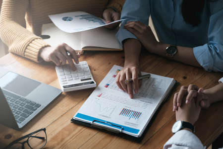 Young accountant marketing team consultants and using calculator to analyze sales growth in the global workplace market. accounting conceptの写真素材