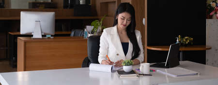 Business woman reading minute of meeting on her notebook in office.の写真素材