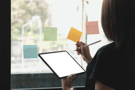 Business woman holding and pointing at digital tablet with blank screen in coffee shop.