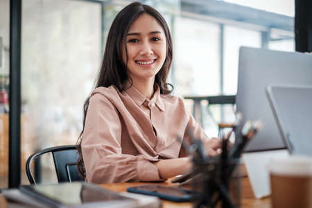 Young Pretty business woman smiling and sitting at home office. work from home concept.の写真素材