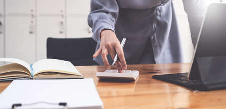 Accountant hand holding pen and using calculator to analyze sales growth in the global workplace...