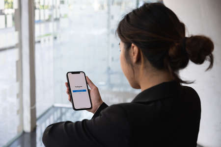 CHIANG MAI, THAILAND - MAR 01, 2021: A woman hand holding iphone with login screen of instagram application. Instagram is largest and most popular photograph social networking.のeditorial素材