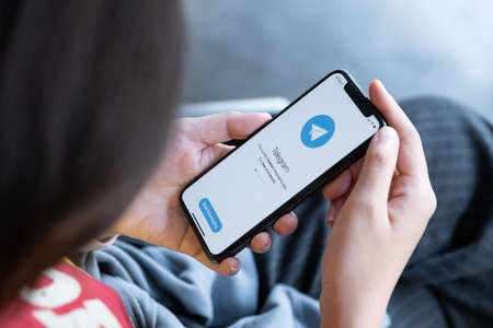 CHIANG MAI, THAILAND, MAR 03, 2021 : Woman hand holding iPhone X with social networking service Telegram on the screen. iPhone 10 was created and developed by the Apple inc.のeditorial素材