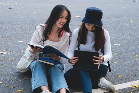 Two students are sitting in university during reading a book and communication. Study, education, university, college, graduate concept.の写真素材