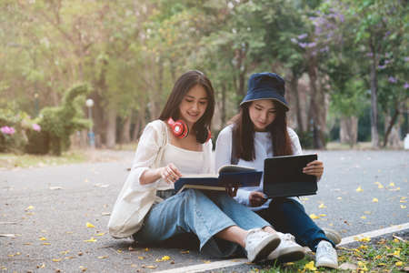 Two students are sitting in university during reading a book and communication. Study, education, university, college, graduate concept.の写真素材