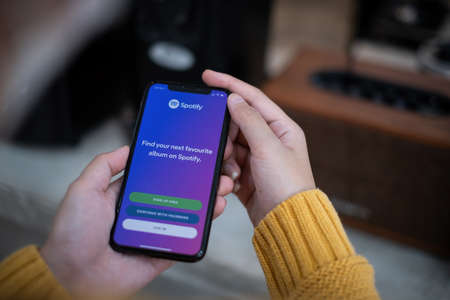 CHIANG MAI, THAILAND APR 14 2021 : Smartphone and using Spotify application on the screen and sync to speaker via bluetooth. Spotify is a music streaming platform developed.のeditorial素材