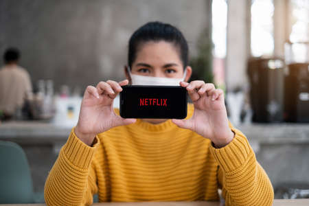 CHIANG MAI, THAILAND APR 14 2021 : Hand holding Apple iPhone with Netflix logo on a screen. Netflix is a global provider of streaming movies and TV series.のeditorial素材