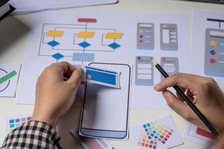 Rear view of developer ux and ui designer about mobile phone app and choosing some interface to...