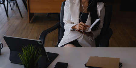 Businesswoman sitting at desk and listening music and joyful with work.の写真素材