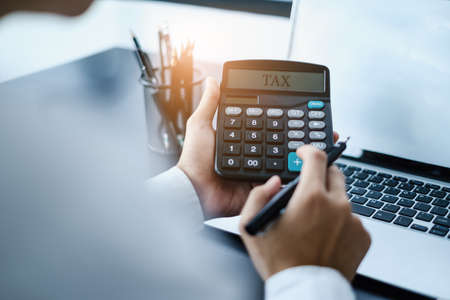 A man calculates taxes with a calculator.の写真素材