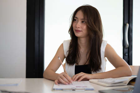 Beautiful secretary listening and taking note at meeting room.の写真素材