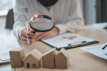 A woman holding magnifying glass and checking house model .Real Estate House Appraisal And Inspection concept.の写真素材