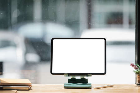 Mockup image of a black digital tablet with white blank screen on wooden desk.の写真素材