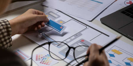 A close-up of an ux ui developer and an ui designer working on a mockup icon interface for a mobile...