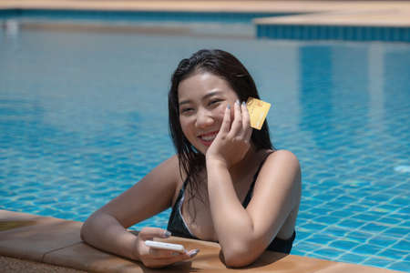 Young woman with bikini in pool using smartphone and holding credit card for shopping online. Everywhere Online shopping concept.の写真素材