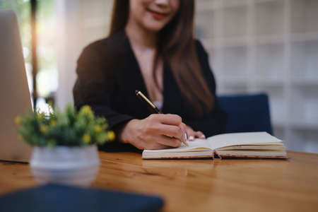 A woman studying webinar by laptop computer and taking note.