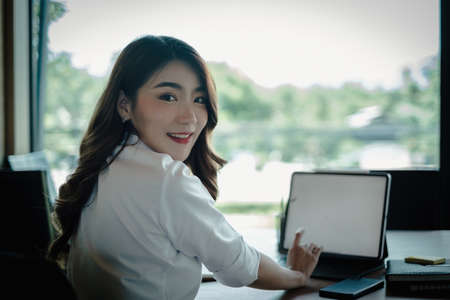 business woman sitting in office with laptop computer on deskの写真素材