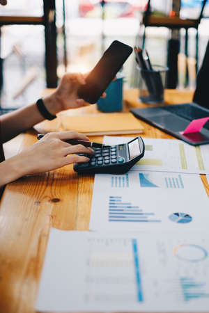 Business woman hand holding pen and cell phone with bank savings account application, account or saving money or insurance conceptの写真素材