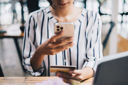 Woman enjoy with online shopping application on cell phone and use camera to scan credit card for fill number to paymentの写真素材