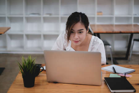 Asian Business woman focus on video call meeting and sitting in office with laptop computer on...