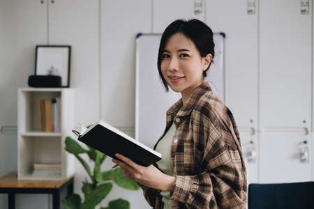 Portrait of cheerful asian woman with casual life on desk in home office. Concept of young business people working at homeの写真素材