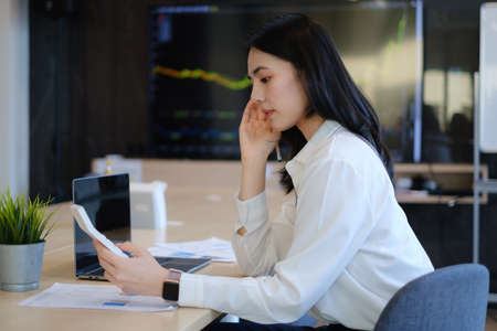 Cheerful young asian woman working with computer at home. Student female in living room. online learning, studying , online shopping, freelance, asean conceptの写真素材