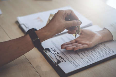 Agents are giving house keys of customer and holding dollar us bank at agency office. Agreement and Real estate conceptの写真素材