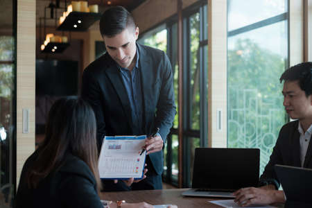 During a business meeting with colleagues, a company marketologist gives a presentation about market plan and investment and pointing at paperwork.の写真素材
